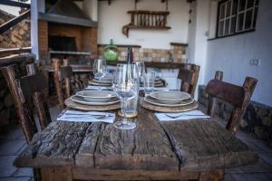 a wooden table with plates and wine glasses on it at CASA RURAL FINCA LOS PAREDONES in El Paso