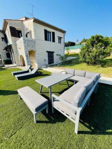 una mesa de picnic y dos bancos en un patio en Magnifique Villa « Le Rocher de Noha »Côte d’Azur, en Vence