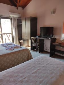 メルロにあるHotel posada barrancas del solのベッドとテレビ付きの机のある寝室 +10枚の写真