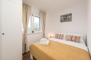 a bedroom with a bed with a yellow blanket and a window at Apartman Enjoy Nin in Nin