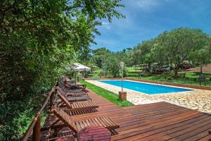 um deque de madeira com cadeiras ao lado de uma piscina em Hotel Chalés Cachoeira 3 Quedas em Brotas