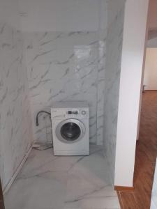 - un lave-linge dans la salle de bains aux murs en marbre dans l'établissement HomeAway, à Bacău