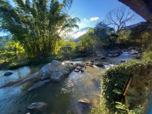 a river with rocks and trees and a bridge at Repousada Sana in Sana