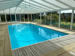 a swimming pool in a house with a white roof at Le Belvédère - Villa 14 personnes - Plage à pied - Piscine couverte et chauffée in Frehel
