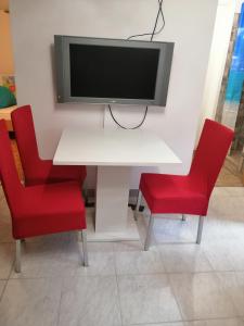 a white table with two red chairs and a tv on a wall at Freya in Lesce