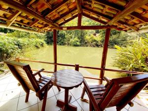 two chairs and a table on a porch with a view of a river at Repousada Sana in Sana