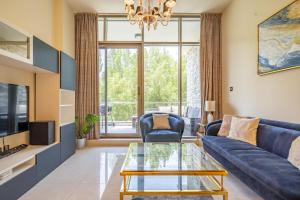 a living room with a blue couch and a glass table at Primestay - Polo Residence in Al Meydan in Dubai