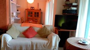 una sala de estar con un sofá blanco con almohadas. en Mirando al mar, en Playa de Xeraco