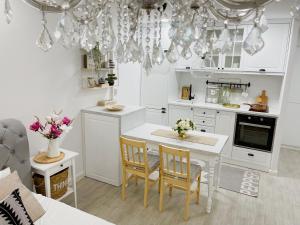 Una cocina con gabinetes blancos y una mesa con sillas. en Apartment MVP Lux, en Kragujevac
