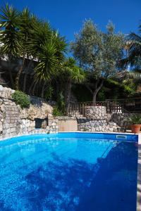 une piscine bleue avec un mur en pierre et des arbres dans l'établissement L'Ulivo Resort, à Vico Equense
