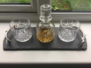 three glasses and a bottle on a black tray at Glenfalloch Beag Apartment, Torvaig in Portree