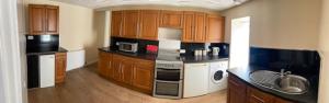 a kitchen with wooden cabinets and black counter tops at 1-2 Dialknowe Holiday Cottage - Wanlockhead in Wanlockhead