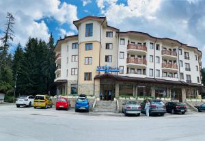 a large building with cars parked in a parking lot at Studio Kris Villa Park in Borovets