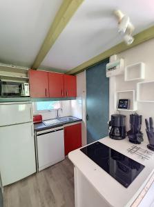 a small kitchen with red and white cabinets at Avignon, joli chalet en campagne très proche de la ville in Avignon