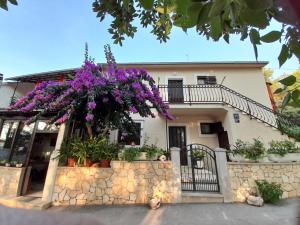 ein Haus mit lila Blumen an einer Steinmauer in der Unterkunft HOUSE-APARTMENTS ELA -MIRCA- FAMILY HOLIDAY in Mirce