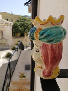 un jarrón colorido sentado en una cornisa junto a un balcón en CASAGIO', en Ragusa