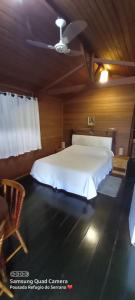 a bedroom with a white bed and a ceiling at Pousada Refugio do Serrano in São Bento do Sapucaí
