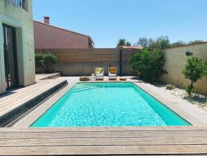een zwembad met twee glazen op een houten terras bij Le Petit Bali Spacieuse Villa pour 8 avec Piscine in Saint Cyprien Plage