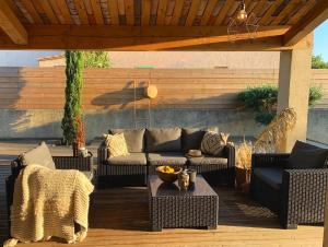 un patio avec des canapés et une table sur une terrasse dans l'établissement Le Petit Bali Spacieuse Villa pour 8 avec Piscine, à Saint Cyprien Plage