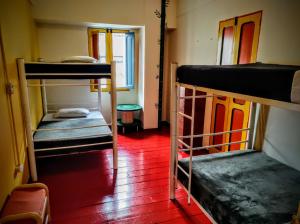 a room with three bunk beds and a red floor at Golden Frog Manizales in Manizales