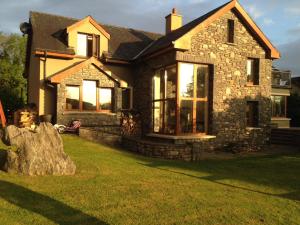 una casa in pietra con una grande finestra su un prato di Golf Course View a Kenmare