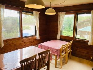 ein Esszimmer mit einem Tisch, Stühlen und Fenstern in der Unterkunft Yado Brodiaea in Myōkō