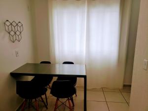 uma mesa de jantar com quatro cadeiras pretas à volta em Residencial Catarina em Florianópolis