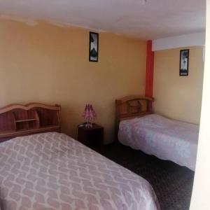 - une chambre avec 2 lits et 2 photos sur le mur dans l'établissement Hostal Puerto Alegre, à Copacabana