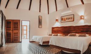 2 camas en un dormitorio con paredes blancas en Dos Mundos Pacific Resort, en Monterrico