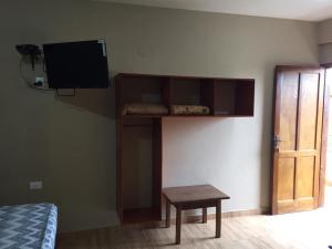 Habitación con TV en la pared y mesa. en Hotel Casa Grande, en Encarnación