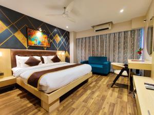 a hotel room with a bed and a blue chair at Hotel Sadbhav Villa in Surat