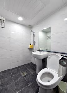 La salle de bains blanche est pourvue de toilettes et d'un lavabo. dans l'établissement Casa Mini Hotel, à Gyeongju