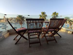 2 Stühle auf einem Balkon mit Hafenblick in der Unterkunft Aquamarine Sea Front Apartments - Second Floor in Marsaskala