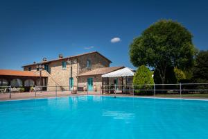 a large blue swimming pool in front of a building at Residence Serristori in Castiglion Fiorentino