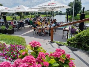 personas sentadas en mesas en un restaurante al aire libre con flores en Hotel Restaurant Bootshaus en Achim
