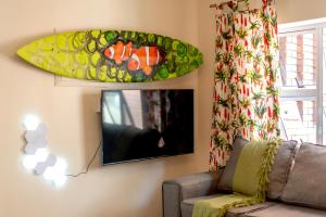a living room with a surfboard hanging on the wall at Walk To Beach 704 Umdloti Holiday Resort in Umdloti