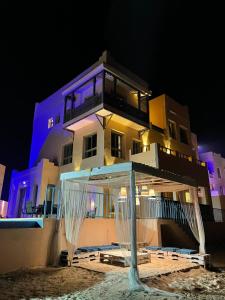 budynek z altaną na plaży w nocy w obiekcie شاليهات ويف -Wave Resort w mieście Al-Chubar