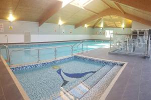 a large swimming pool in a building with a large swimming pool at Exclusive 2 bedroom bungalow Oulten Broad in Carlton Colville