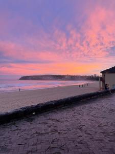 zachód słońca na plaży z ludźmi na piasku w obiekcie Manly Bunkhouse w mieście Sydney