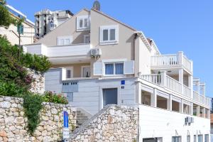 a large white house with a stone wall at Apartment Violeta 2 with parking in Dubrovnik