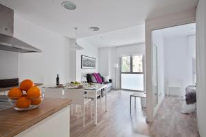 a kitchen and living room with a bowl of oranges on a table at Habitat Apartments Blanca in Barcelona