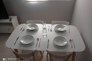 una mesa blanca con platos y utensilios. en Apartamento cabañiles wifi, en Jerez de la Frontera