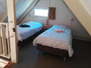 a attic room with two beds and a window at 6-pers vakantiebungalow in het Heuvelland in Simpelveld