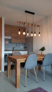 a kitchen with a wooden table with chairs and lights at The purple fox's family home - Veysonnaz in Veysonnaz