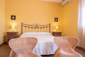 a bedroom with a bed and two wicker chairs at Casa en el pantano de Orellana in Orellana la Sierra