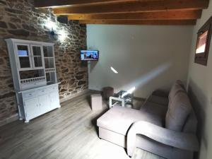 un soggiorno con divano e TV di Apartamentos rurales Casa Gorrión - Mazaricos a Sanfoga