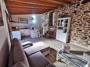 - un salon avec un canapé et un mur en pierre dans l'établissement Apartamentos rurales Casa Gorrión - Mazaricos, à Sanfoga