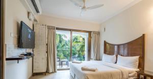 カンドリムにあるCasa Legend Suites Candolim Goaのベッドルーム(ベッド1台、テレビ、窓付)