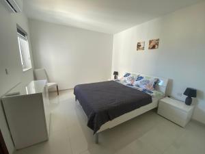 a bedroom with a bed in a white room at Sunshine Apartments Mellieha - modern two bedroom penthouse with terrace in Mellieħa