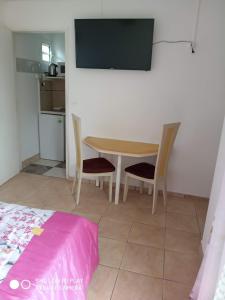 Habitación con mesa, 2 sillas y TV. en Charmant studio dans le sud, idéal pour un couple, en Trois Mares-les Hauts